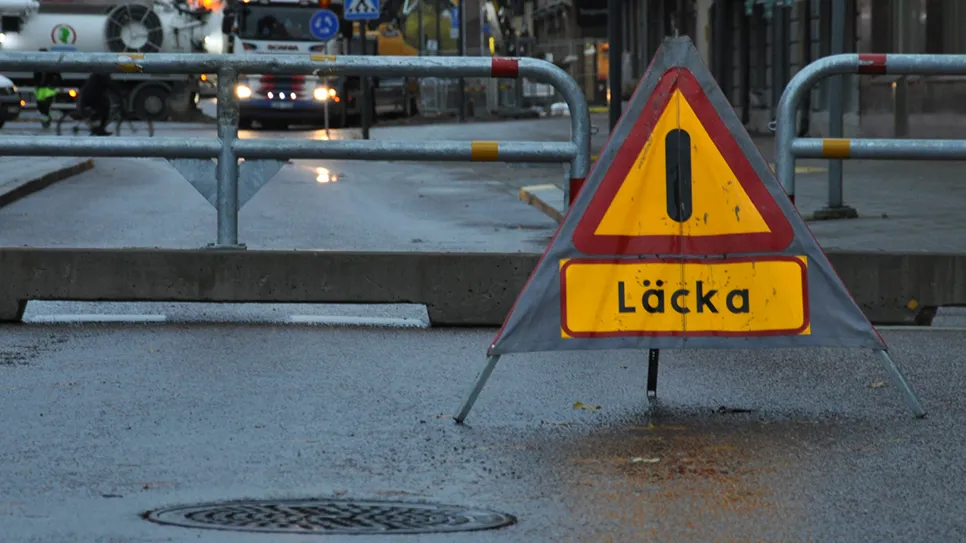 Varningsskylt för vattenläcka på väg.
