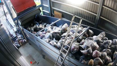 Textilier lastas av i återvinningsanläggning.