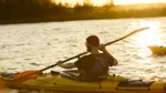 En man padlar kajak i solen.
