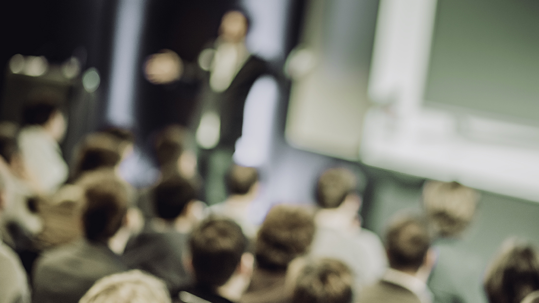En diffus bild av en man som håller en föreläsning.