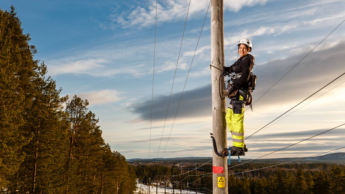 Person arbetare på en kraftledningsstolpe.