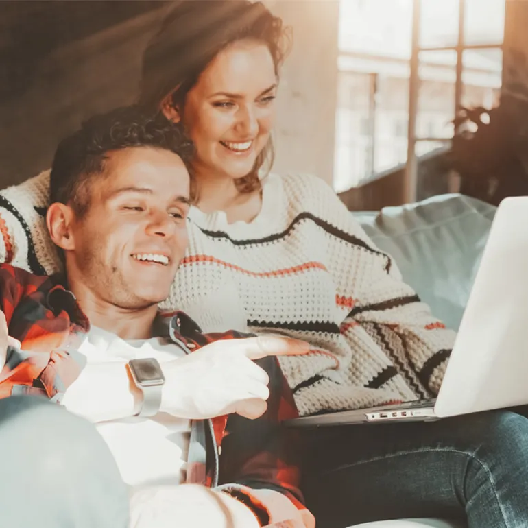 Kille och tjej i en soffa framför en dator.