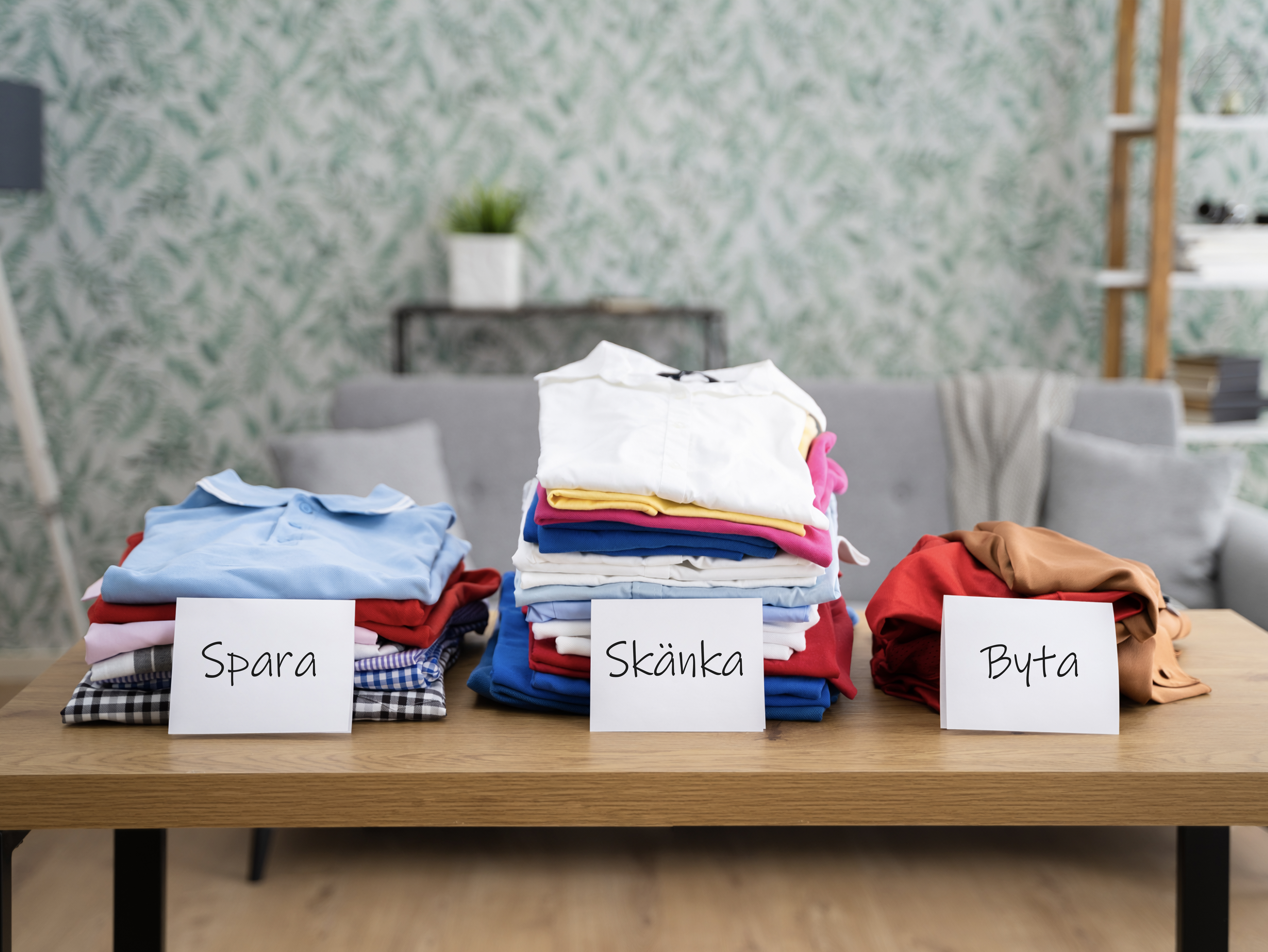 Vikta klädhögar uppdelade efter vad som ska sparas, skänkas eller bytas.