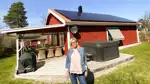 Bild på mikroproducenten Eva Eimehag som står framför sitt hus med nyinstallerade solceller på taket.