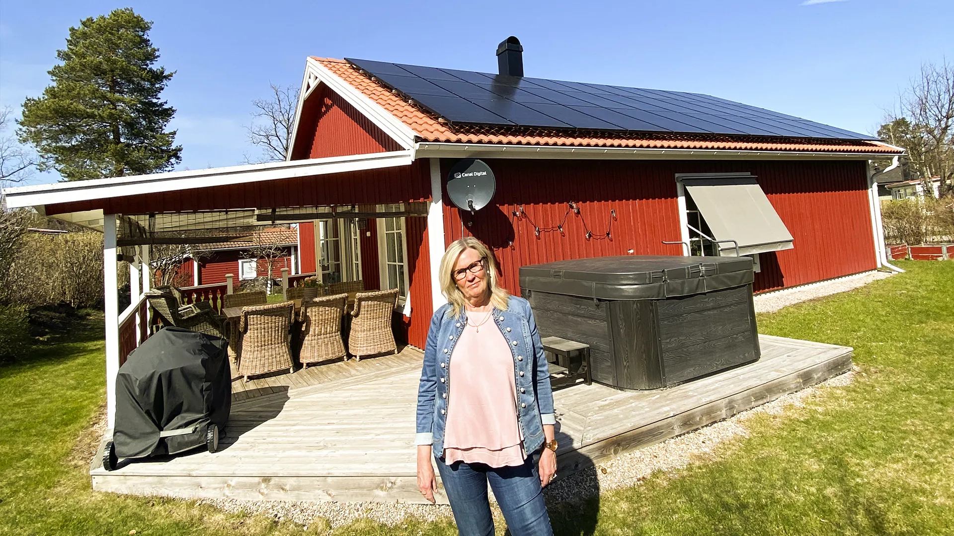 Bild på mikroproducenten Eva Eimehag som står framför sitt hus med nyinstallerade solceller på taket