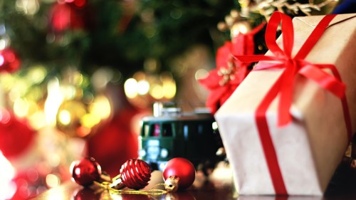 En inslagen julklapp med julbelysning i bakgrunden.