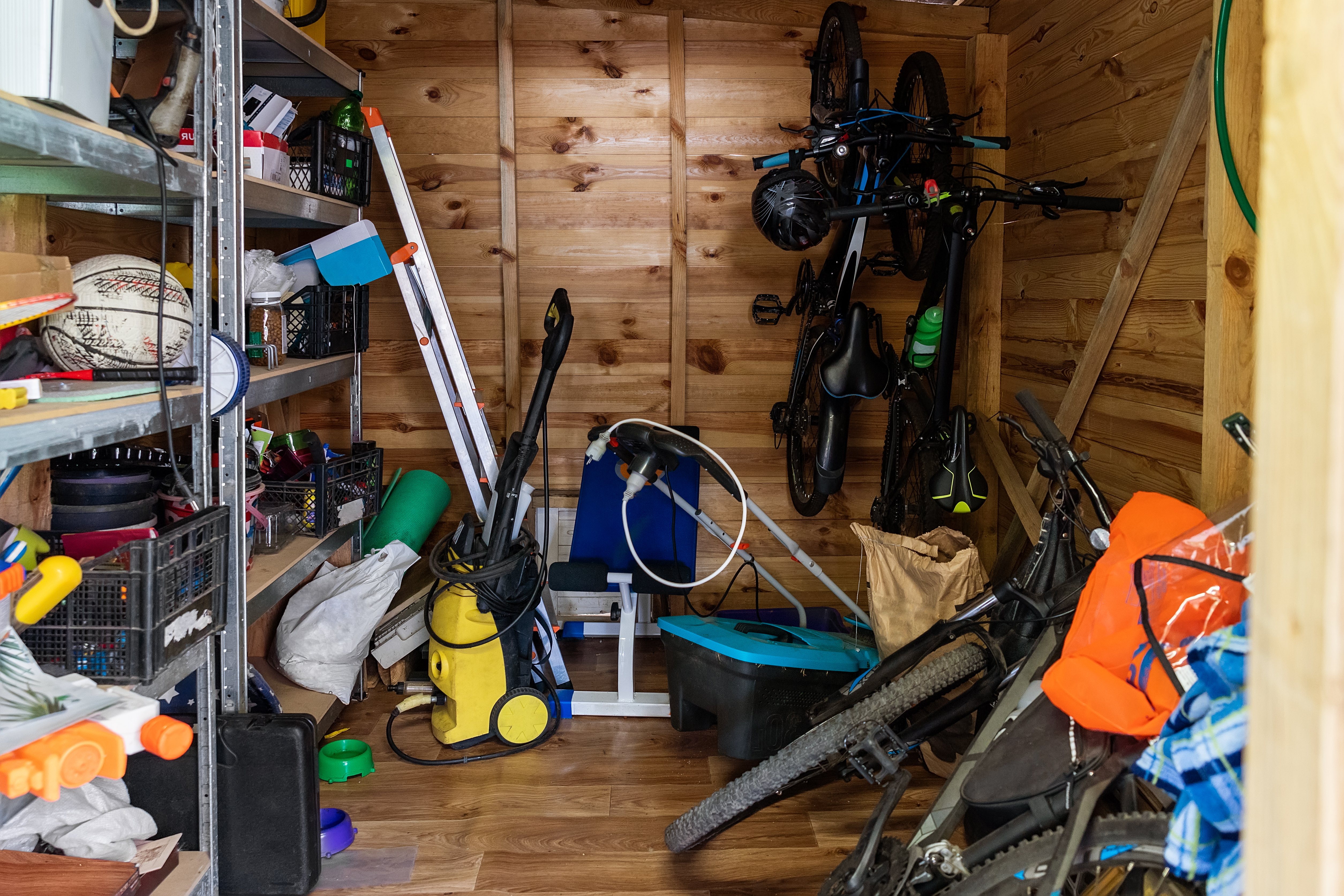 Ett förråd med hyllor, verktyg, cyklar och diverse utrustning.