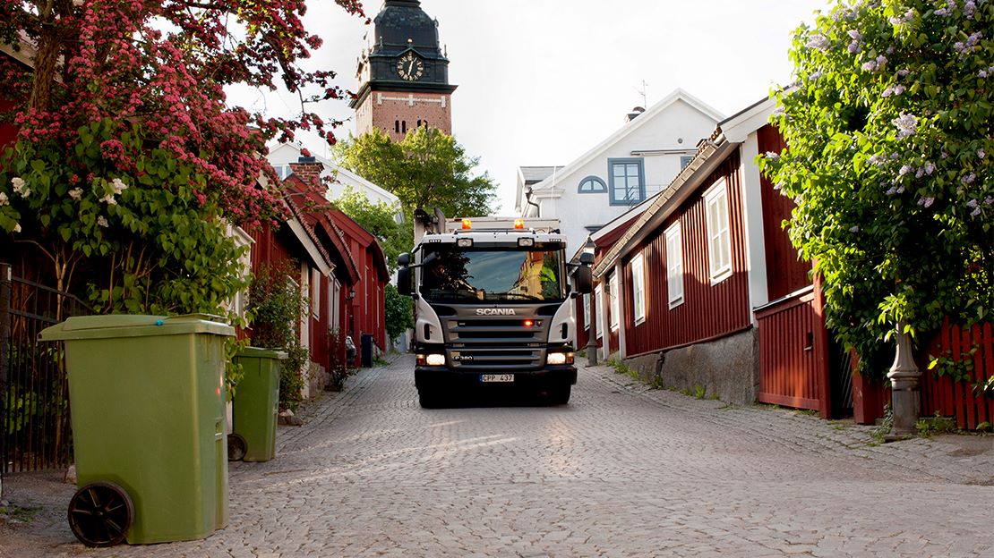 Sopbil på smal stadsgata.