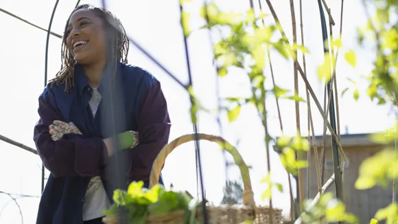 Leende kvinna bakom korg med växter.