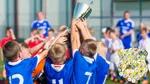 Barn i idrottslag håller i pokal.