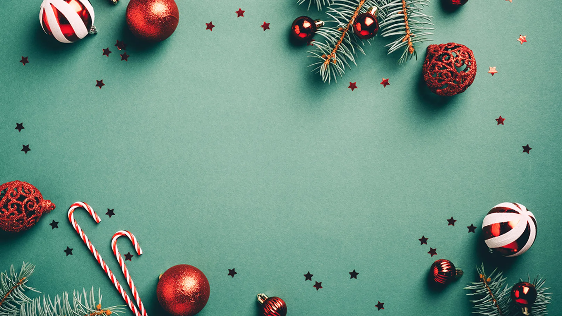 Julkulor, granris och polkagriskäppar som ligger på en grön bakgrund