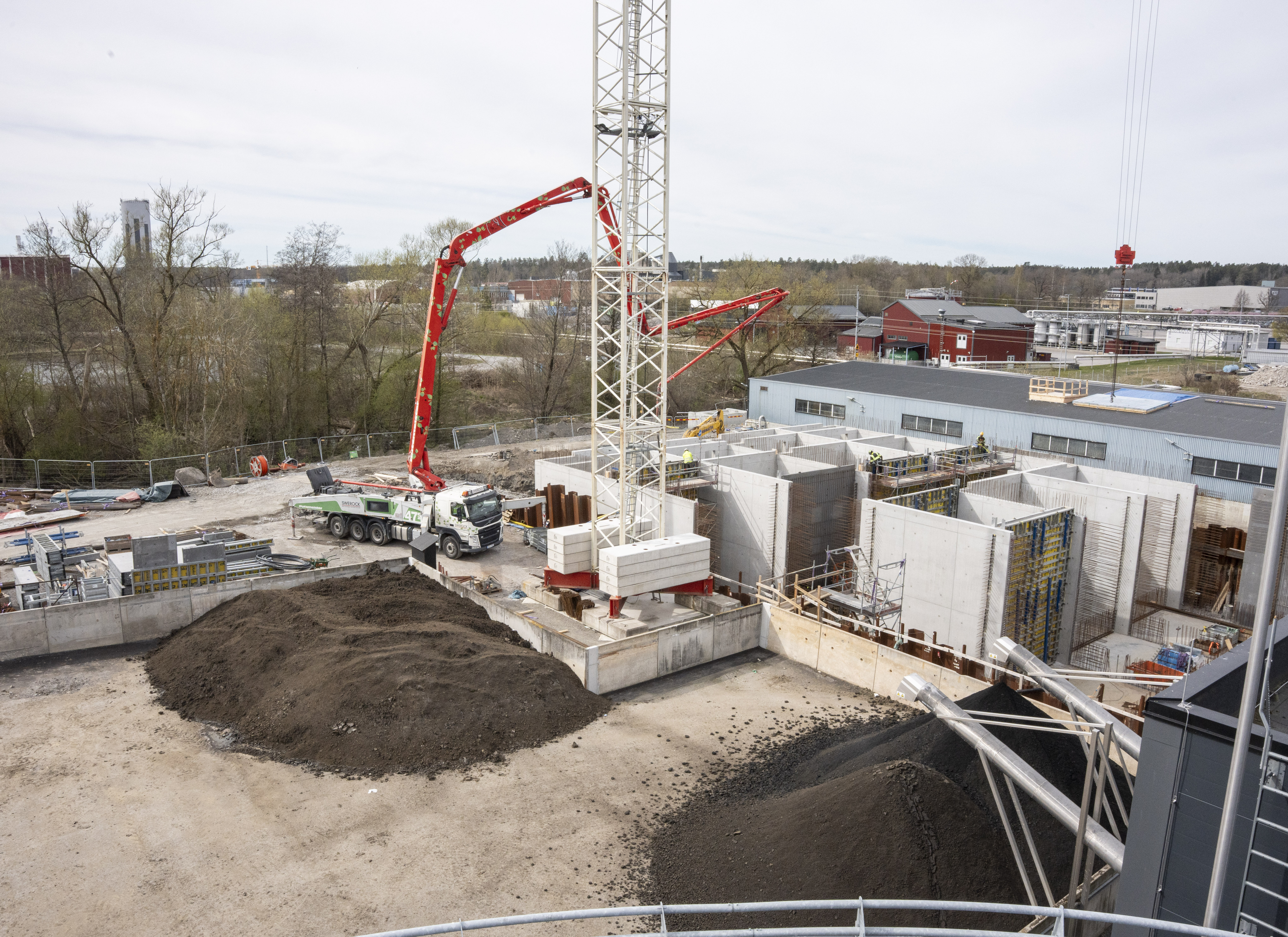 Vy snett ovanifrån av bygget på Strängnäs avloppsreningsverk där en ny byggnad står halvfärdig.