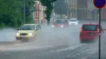 En bilväg i stadsmiljö med vatten och spöregn.