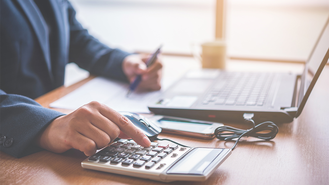 Miniräknare och laptop på ett bord.