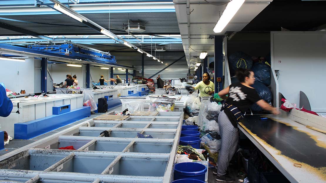 Textilier sorteras i återvinningsanläggning.