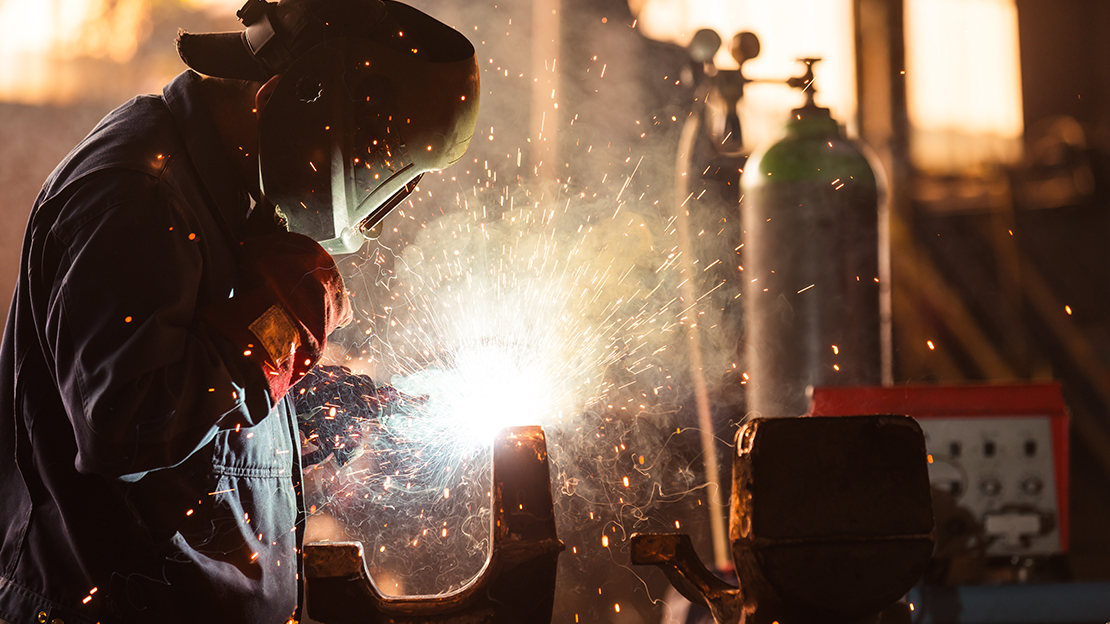 Person i skyddskläder som svetsar.
