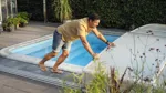 Man tar bort ett poolskydd från pool.