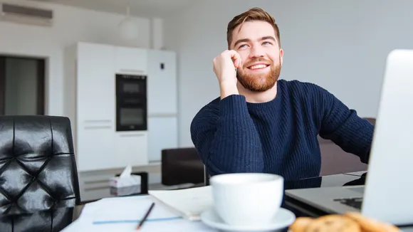 Man pratar i mobiltelefon vid datorn.