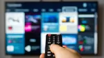 Person med fjärrkontroll väljer tv-tjänster.